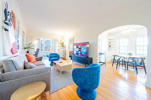 A living room with a grey couch, a blue chair, a wooden table, and a television.