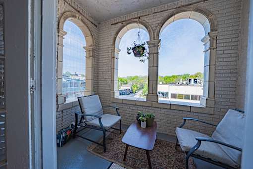 A balcony with two chairs and a table with a potted plant on it.