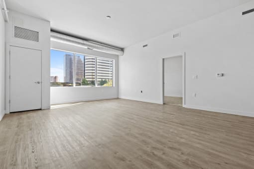 an empty living room with white walls and a window