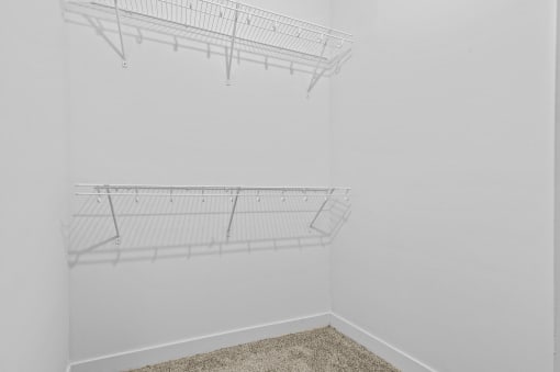 an empty closet in a room with white walls and a wire shelf on the wall