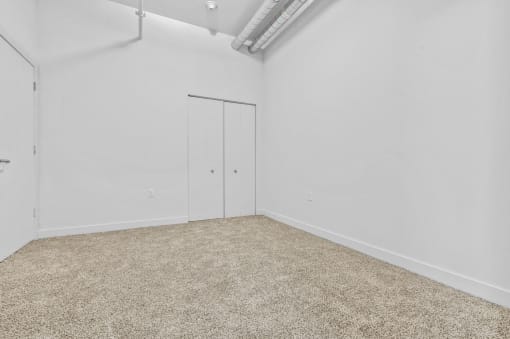 an empty room with white walls and carpet and a door