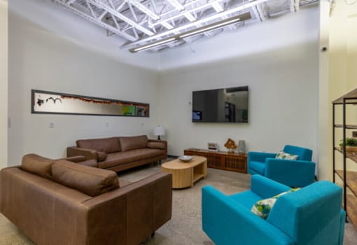 A living room with a brown couch, blue chair, and a painting on the wall.