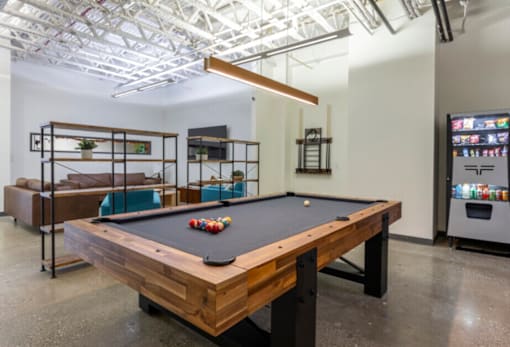 A pool table with a wooden top and black felt is in the center of the room.
