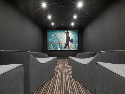 a home theater with couches and a screen on the wall