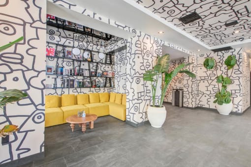 a lobby with a yellow couch and a wall with graffiti on it