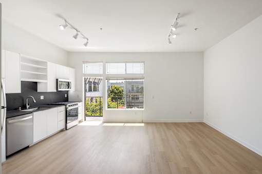 A kitchen with white cabinets and a window overlooking a street.