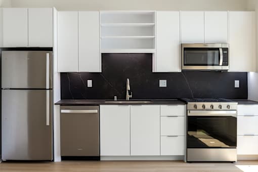 A modern kitchen with white cabinets and stainless steel appliances.