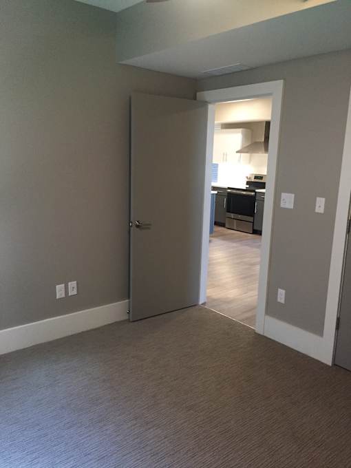 a bedroom with a door open to a hallway and a kitchen