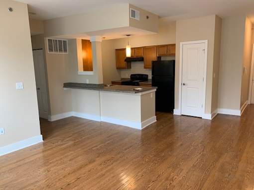 an empty living room and kitchen with a wood floor
