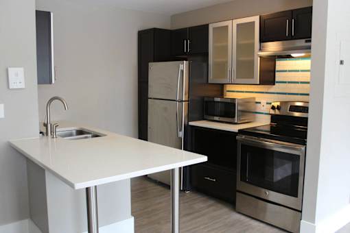 a kitchen with black and white cabinets and stainless steel appliances