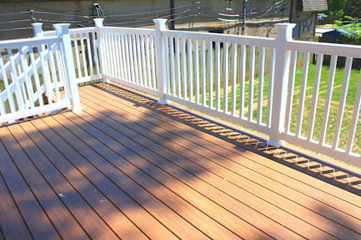 a composite deck with white railing and wood flooring