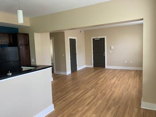 an empty living room and kitchen with a wood floor