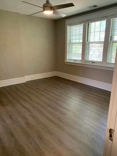 an empty room with wood floors and a ceiling fan