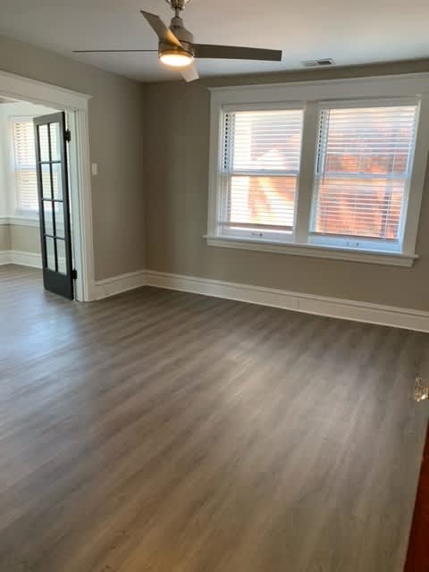 an empty living room with wood floors and a ceiling fan