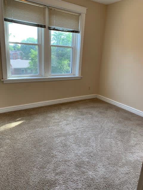 a room with a carpeted floor and two windows