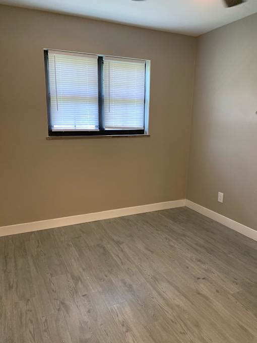 an empty room with wooden floors and a window