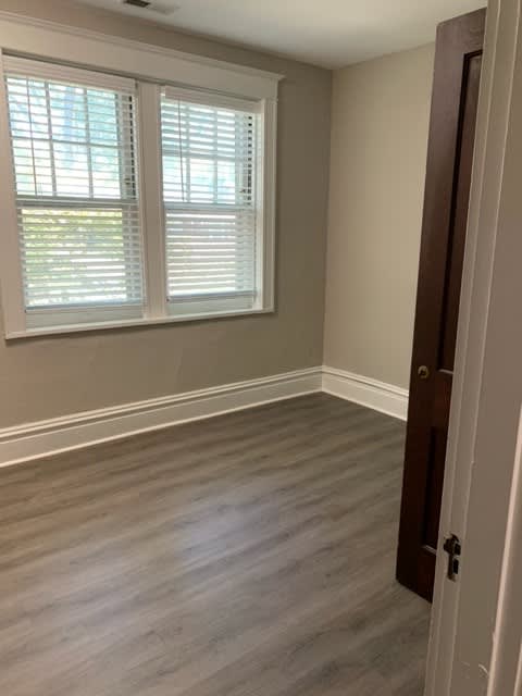 an empty room with wooden floors and two windows