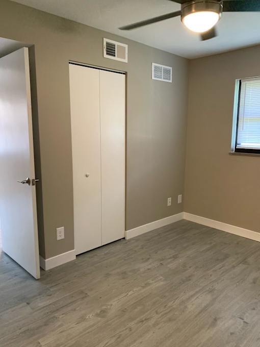 a bedroom with a closet and a window and a hard wood floor