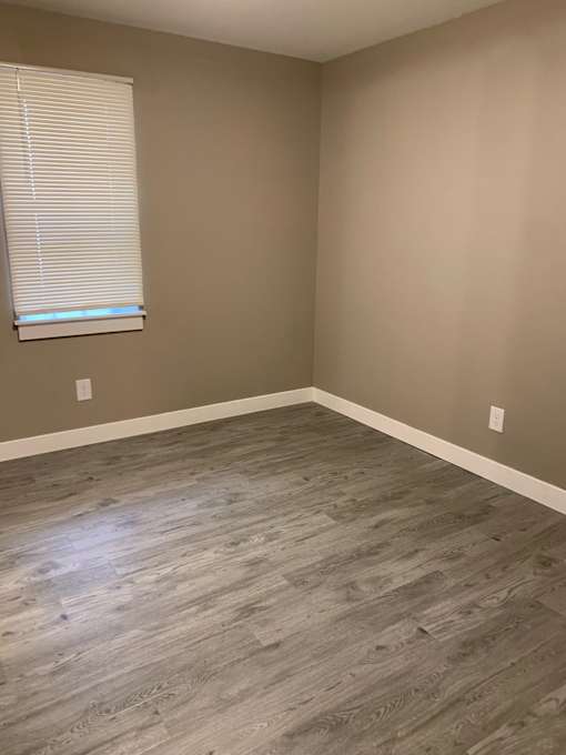 an empty room with wood floors and a window
