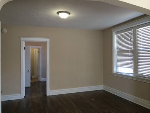 an empty living room with wood floors and a large window