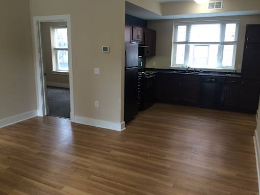 an empty kitchen with wood flooring in an empty house