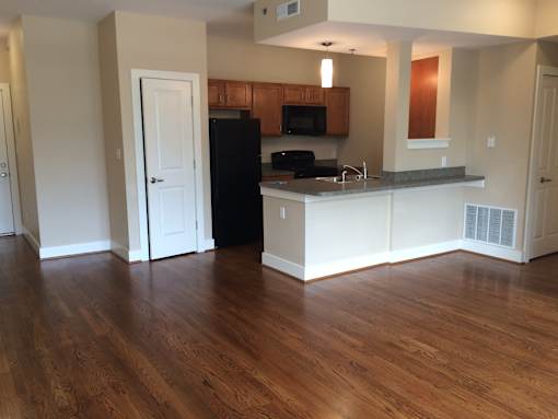 an empty living room and kitchen with wood floors