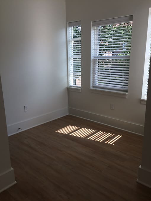 an empty room with wooden floors and two windows