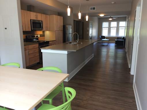 an open kitchen and dining area with green chairs and a table