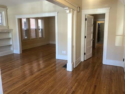 a living room and dining room with wood flooring and white walls
