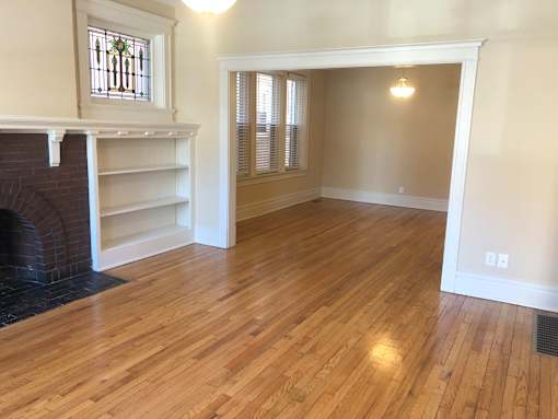 an empty living room with wood flooring and a fireplace