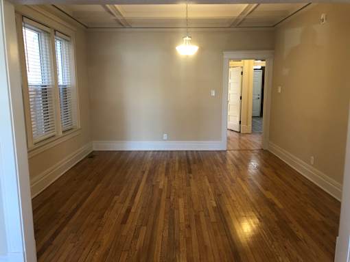 an empty living room with wooden floors and white walls