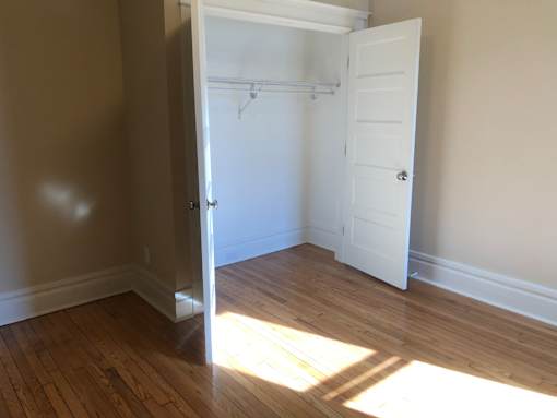a bedroom with a closet and a wooden floor and a white door