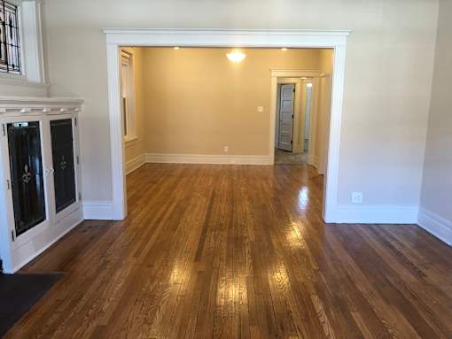 a living room and dining room with wood floors and white walls