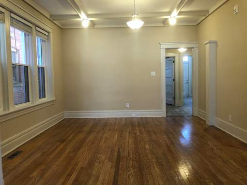 an empty living room with a hard wood floor and windows