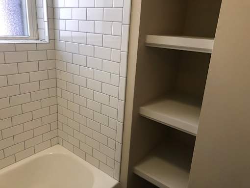 a small bathroom with white tile and a window