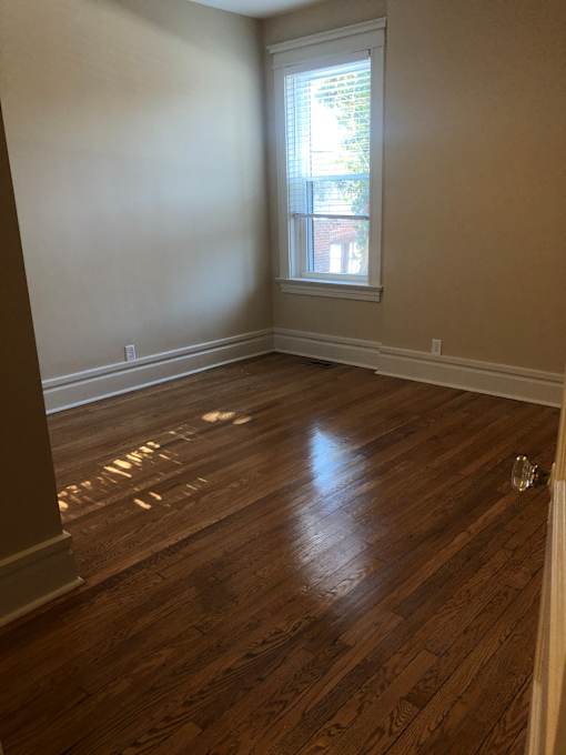 an empty room with wood flooring and a window