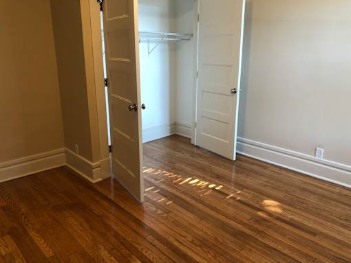 a bedroom with wood floors and an open closet