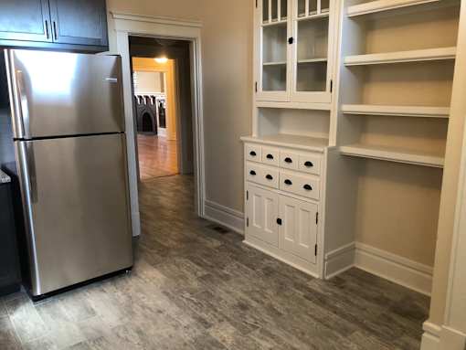 a kitchen with white cabinets and a stainless steel refrigerator