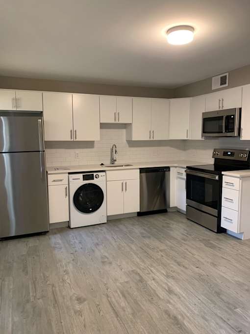 a renovated kitchen with white cabinets and stainless steel appliances