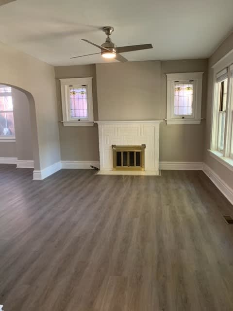 an empty living room with a fireplace and a ceiling fan