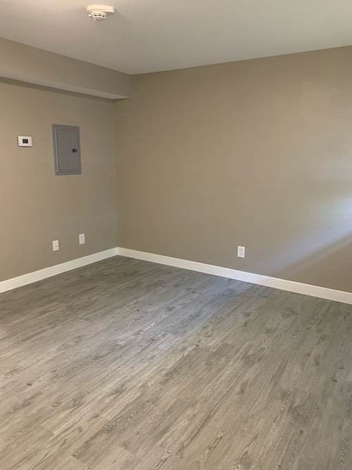 a empty room with wood flooring and tan walls
