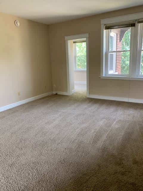 an empty room with a carpeted floor and two windows