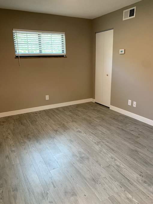 an empty room with wood floors and a window