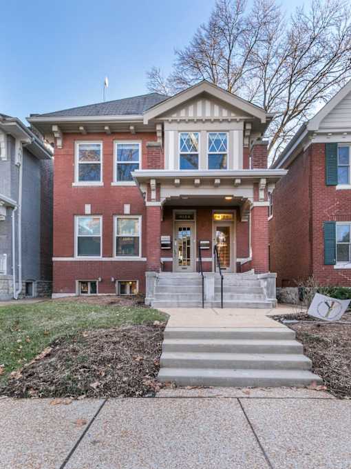 A red brick house with a white trim and a front porch.