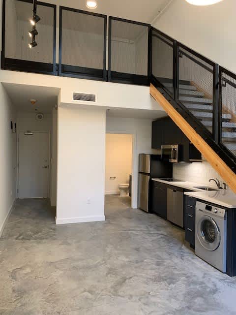 A kitchen with a washing machine and a staircase.