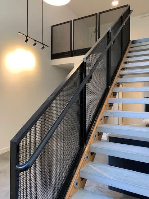 A staircase with a black railing and a light on the wall.