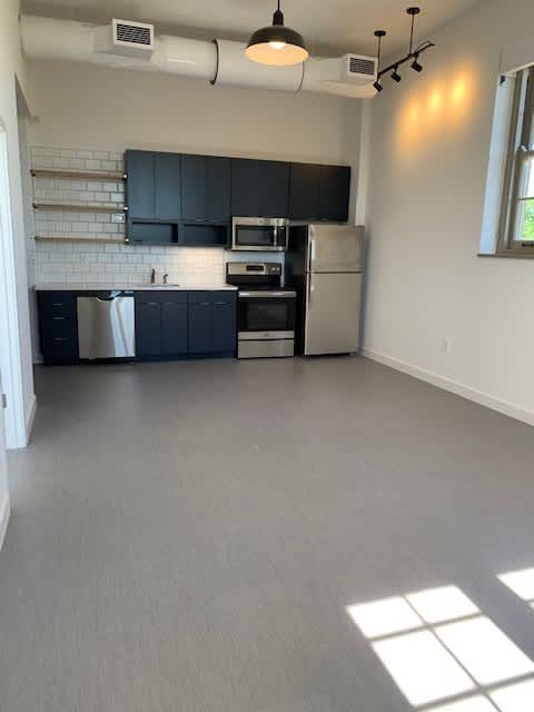 A kitchen with a refrigerator, microwave, and oven.