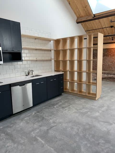 A kitchen with black cabinets and a white tiled backsplash.