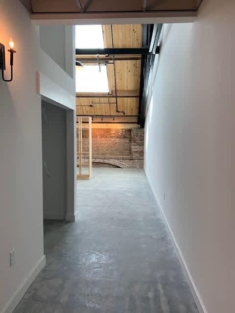 A long, empty hallway with a brick wall in the distance.