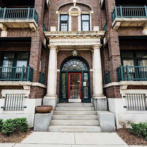 A red door is flanked by two green balconies.